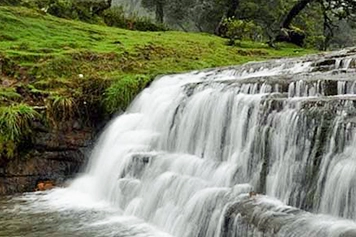 Serene view of Bear Shola Falls in Kodaikanal, surrounded by lush greenery and cascading water.
